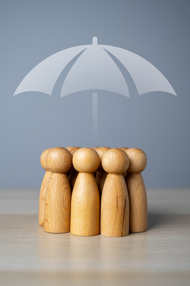 Jeu de quilles sur une table avec un dessin de parapluie au dessus, represente un groupe de personnes ou une famille et la prevoyance
