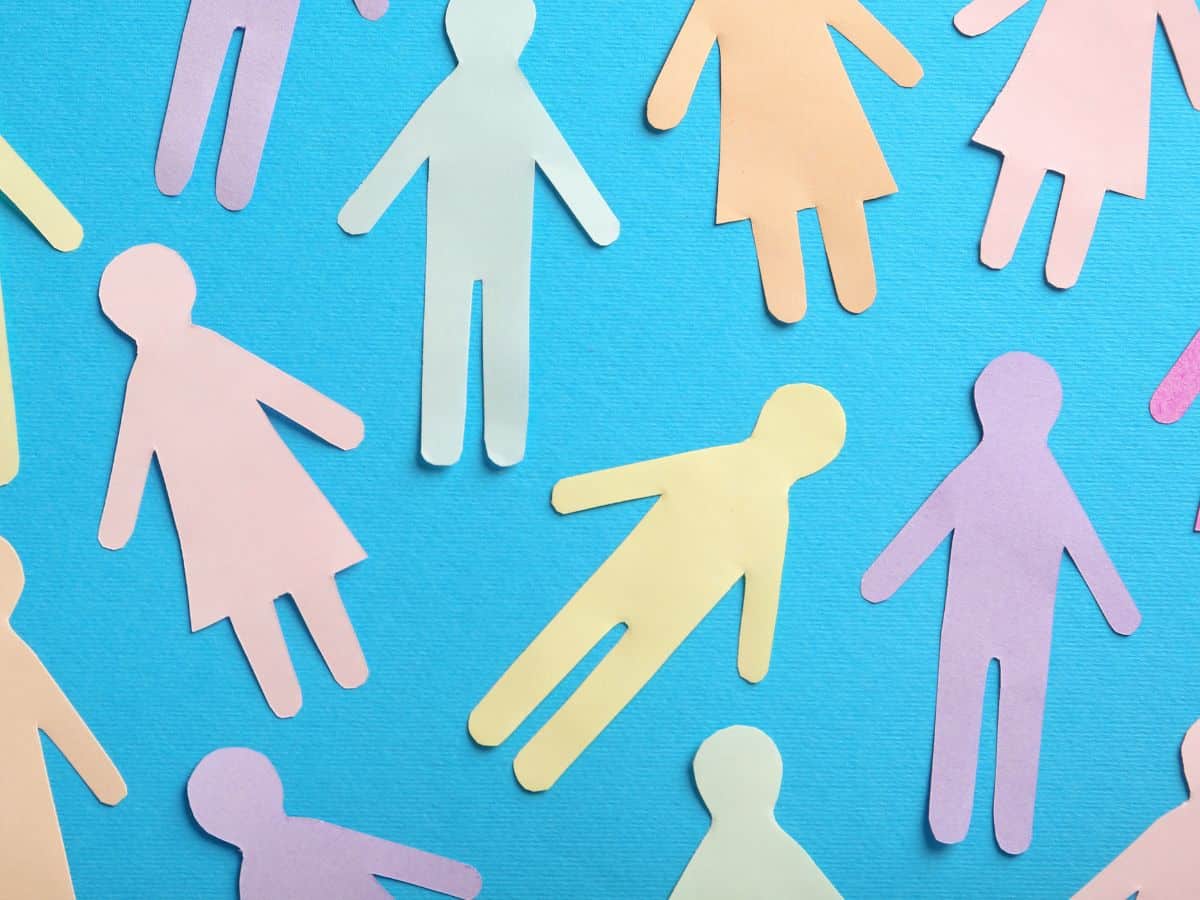 Sur un fond bleu des silhouettes en papier de personnes de différentes couleurs