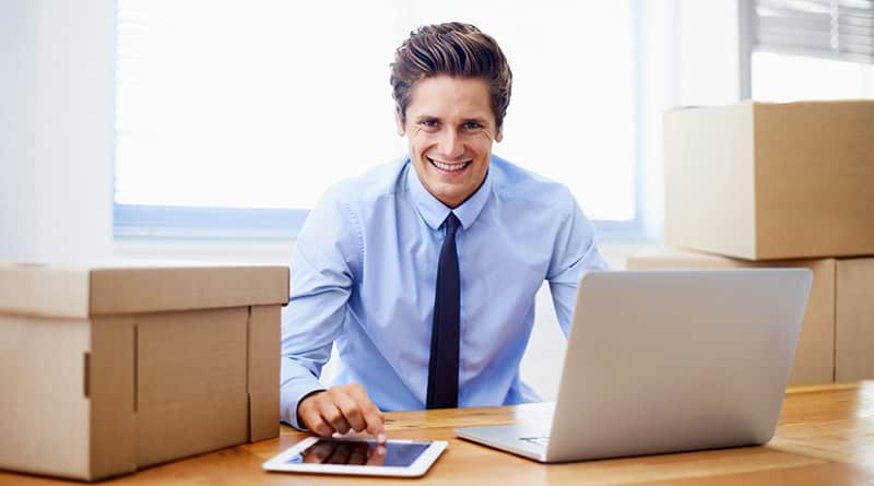 homme au bureau devant son pc avec des cartons pour déménagement professionnel