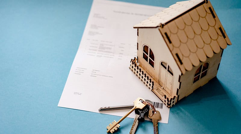 Maquette maison avec contrat et clé de logement sur fond bleu