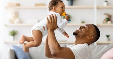 pere porte son fils dans les bras devant lui à la hauteur de son visage