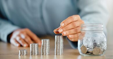 homme fait 4 piles de pieces sur une table avec un bocal plein de pieces