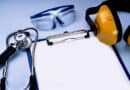 Sur un fond bleu ciel, un stéthoscope, des lunettes de protection, un casque anti bruit et un bloc papier