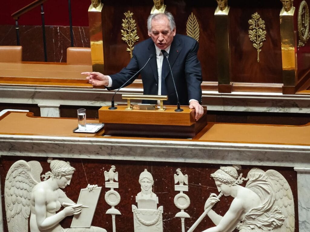 Un homme, au premeir, plan, parle dans un micro. Il s'agit d'Alain Bayrou, premier Ministre, prend la parole à l'assemblée nationale.
