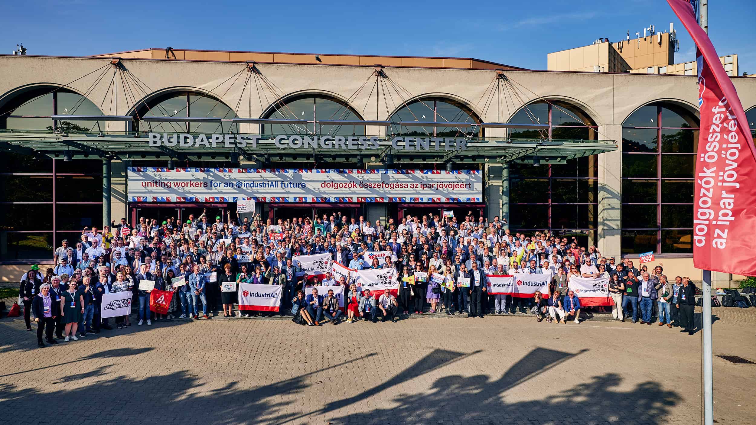 Une centaine de personnes pausent devant un bâtiment en arches qui accueille le congrès du syndicat industriall