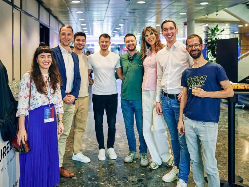 Groupe de 8 jeunes syndicalistes européens en arc de cercle dans le hall lors du congrès 2025 Industriall Europe