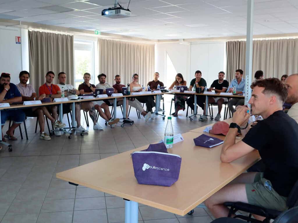 Des jeunes femmes et hommes autour d'une table en U en réunion