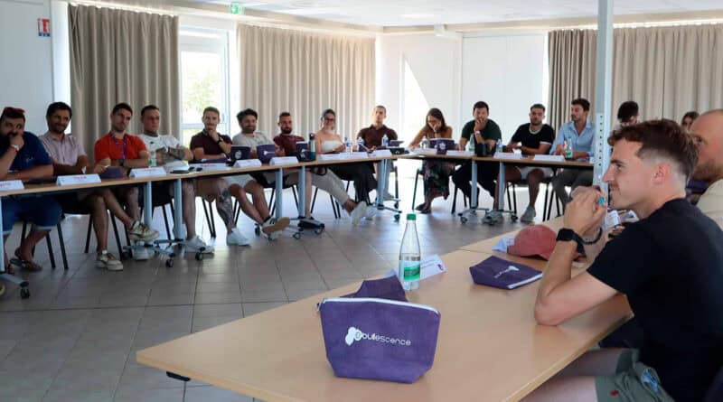 Des jeunes femmes et hommes autour d'une table en U en réunion