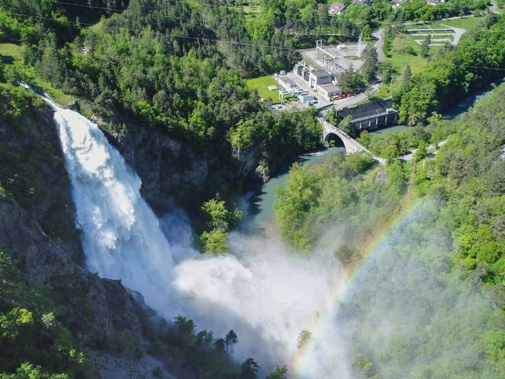 cascade d'eau qui se jette dans la vallée au second plan l'usine hydroélectrique