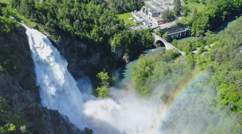 cascade d'eau qui se jette dans la vallée au second plan l'usine hydroélectrique