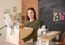une jeune femme porte un carton avec ses affaires de bureau
