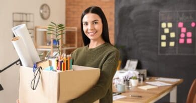 une jeune femme porte un carton avec ses affaires de bureau
