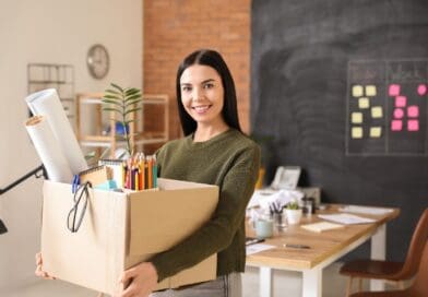 une jeune femme porte un carton avec ses affaires de bureau