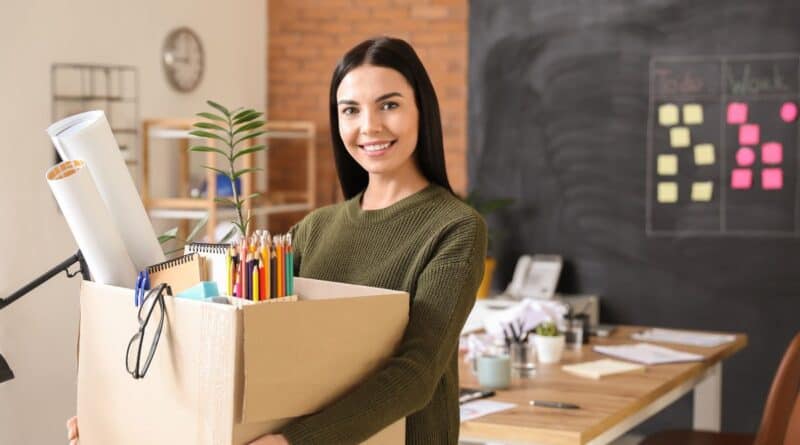 une jeune femme porte un carton avec ses affaires de bureau